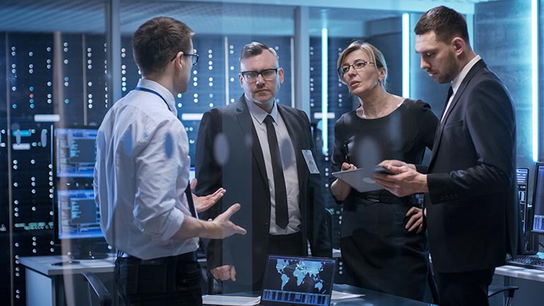 Three men and woman having discussion in network operations center