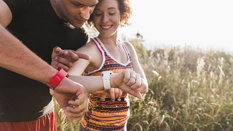 couple checking smart watches while exercising 