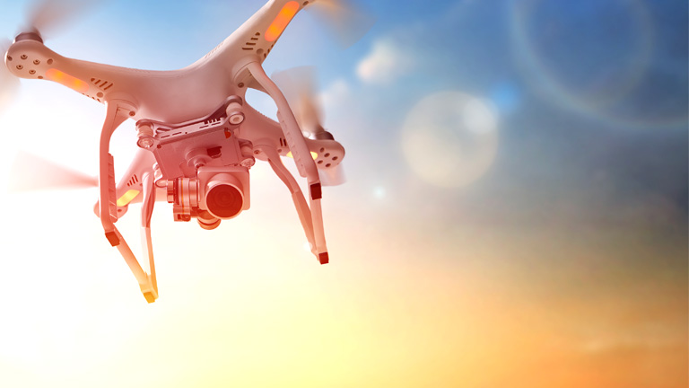 white drone flying at sunset