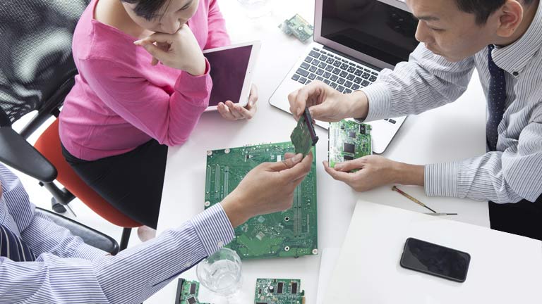 Two men and woman reviewing technology products.