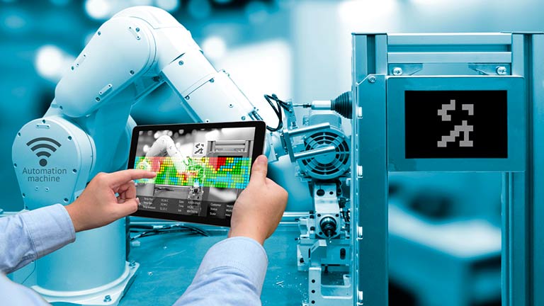 worker using tablet computer to monitor industrial robotic arm