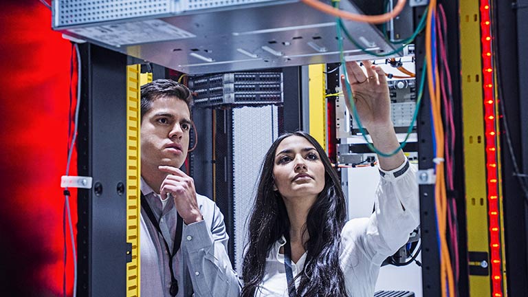 young man and woman inspecting equipment in computer datacenter