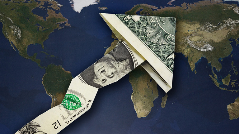 dollar bill folded into an arrwo and placed upon a world map