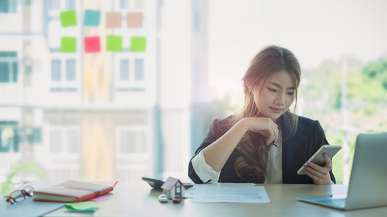 young woman at desk using smartphone