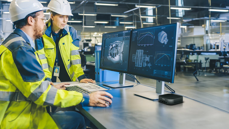 man  and woman at desk looking at computer monitors