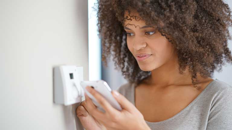 Woman controlling thermostate temperature via mobile device