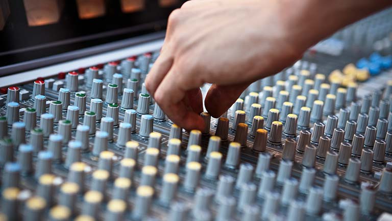 person modifying settings on audio mixer console