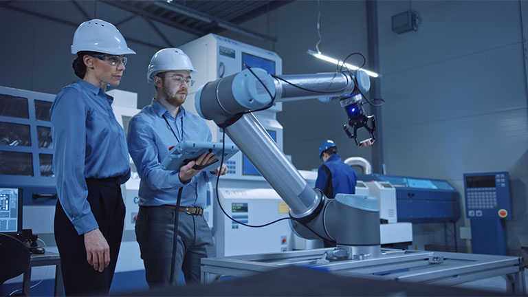 man and woman watching robotic arm