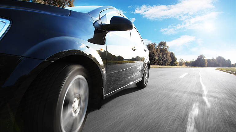 Close up of front wheel of a car as it drives down a road